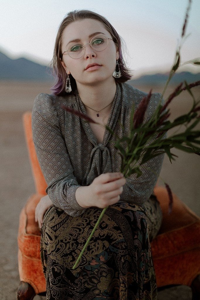 Woman sits in orange vintage chair with lavender dry lake bed