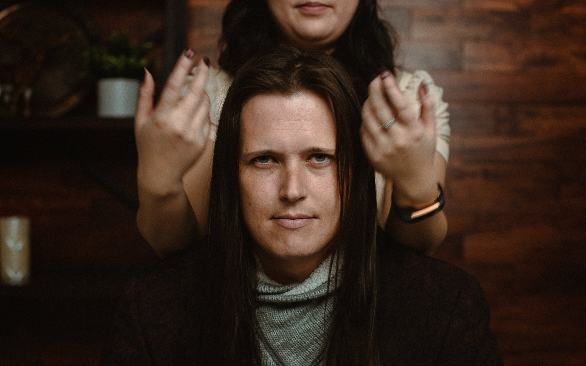 Man looks at camera while girlfriend touches his long hair