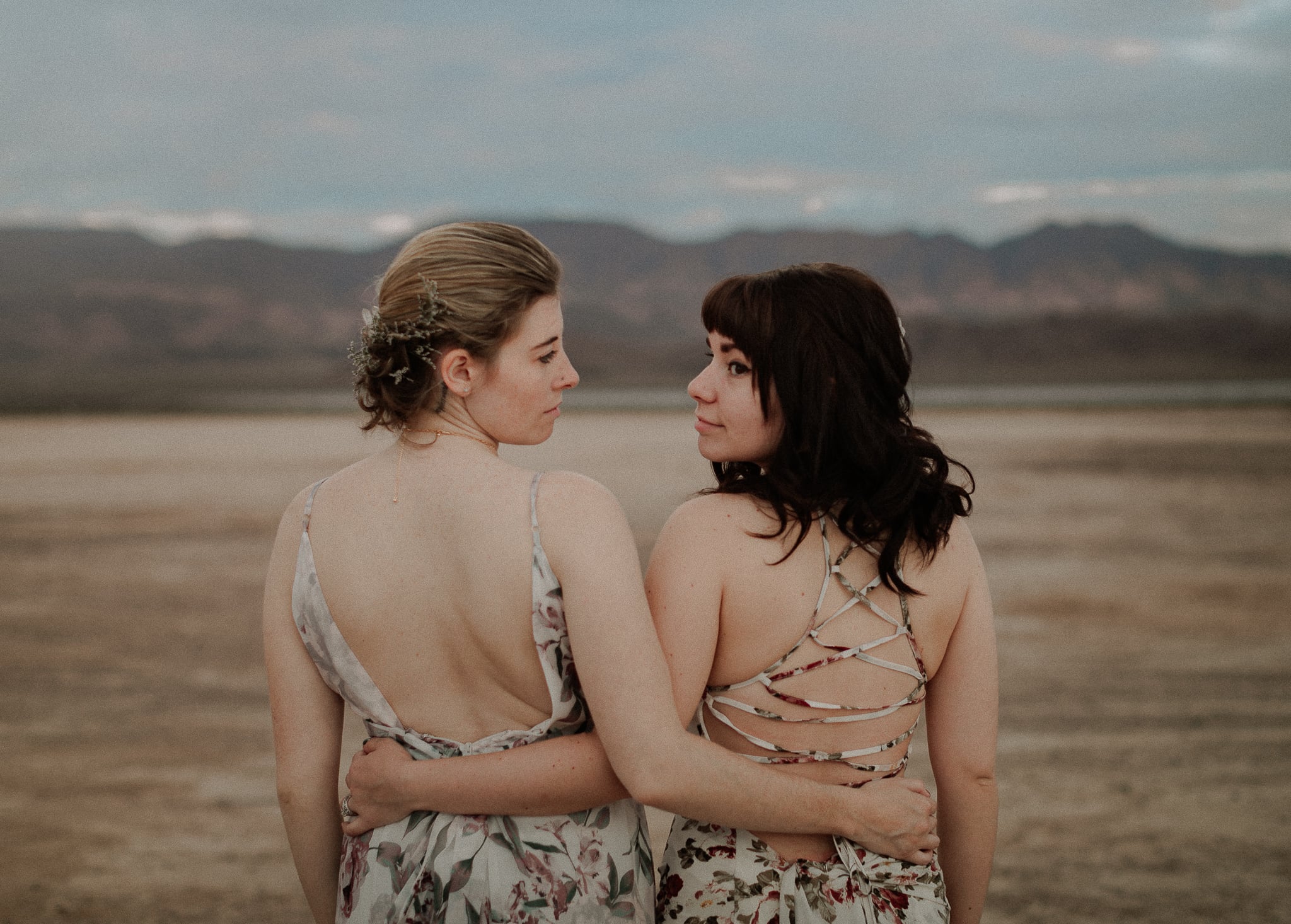 Bride and Maid of Honor look at each other at dry lake bed