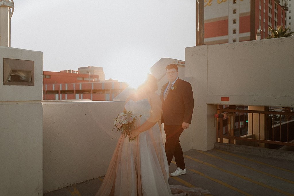 Golden hour sunflare bride and groom pose on top of El Cortez Parking Garage