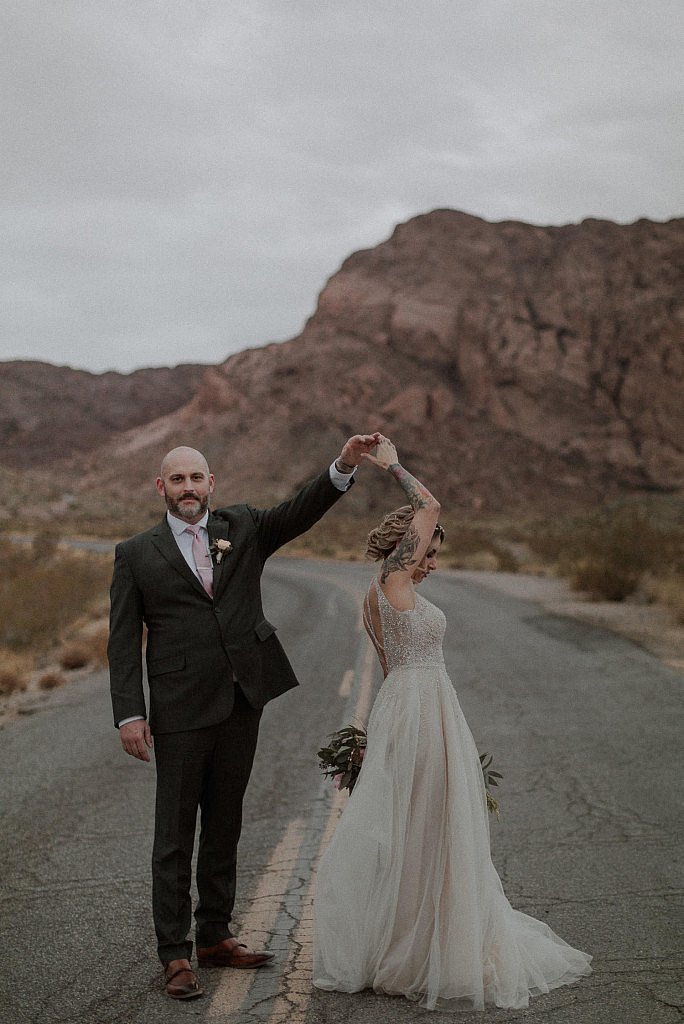 Bride and groom walk on road for adventure elopement in Las Vegas