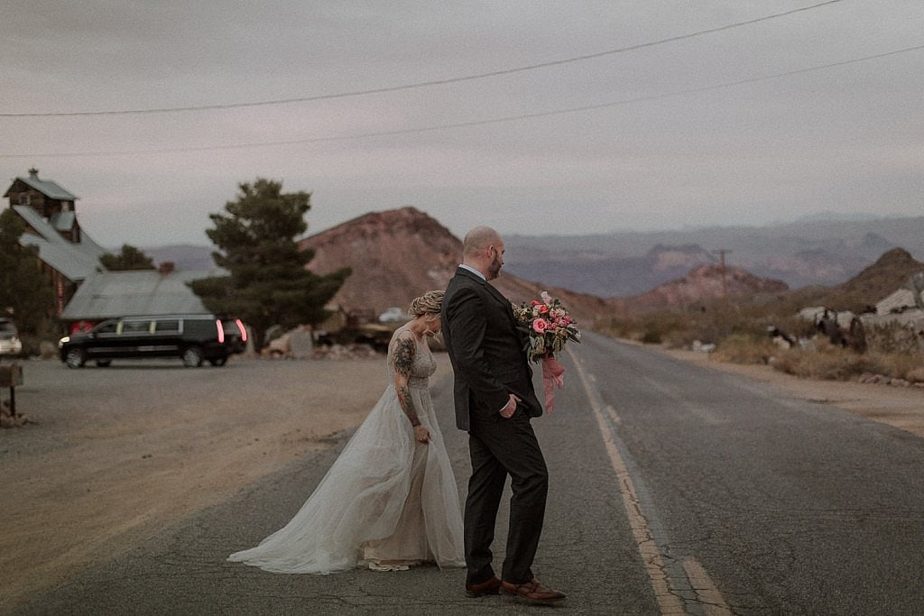 Bride and groom walk on road for adventure elopement in Las Vegas