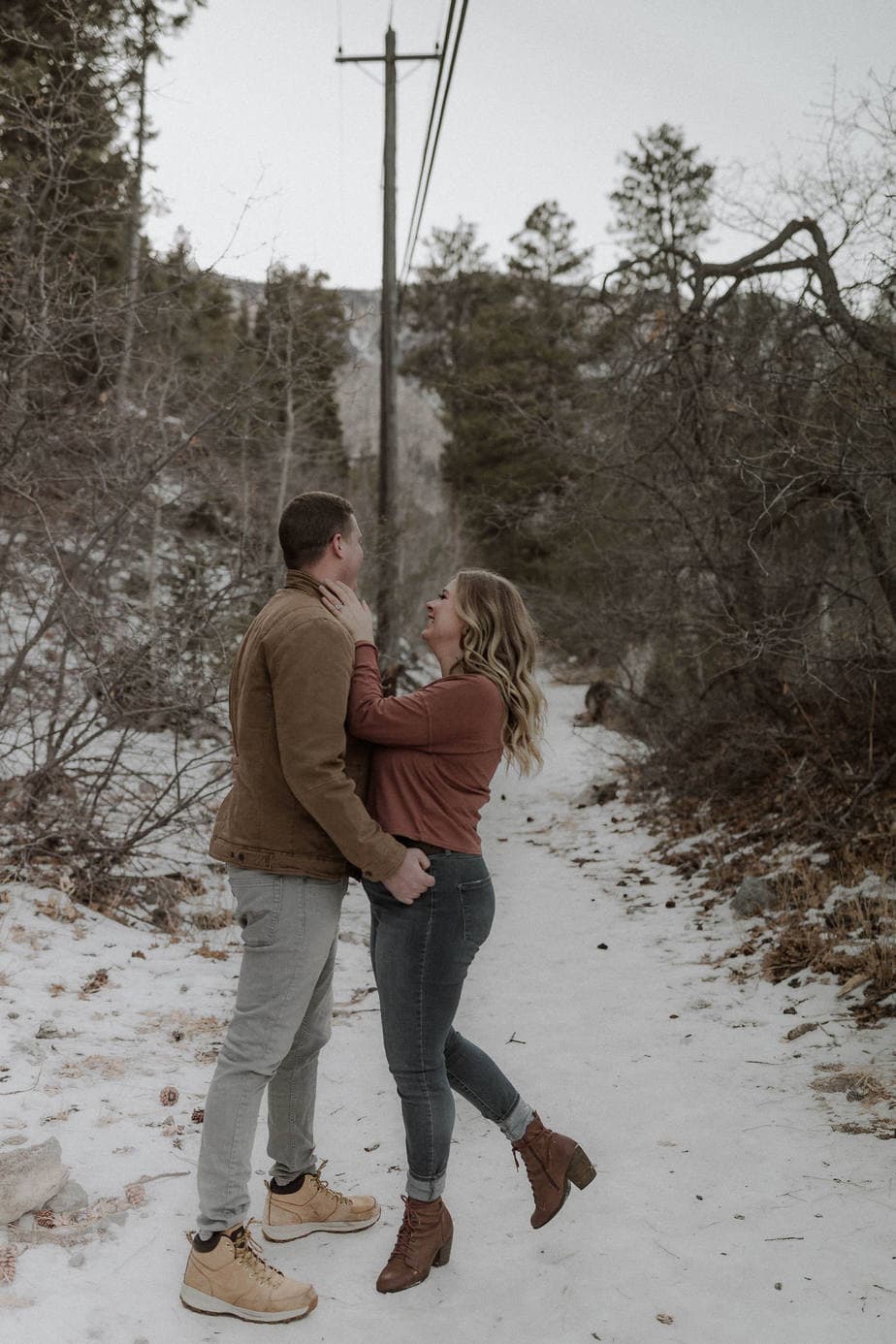 A winter Oregon engagement session with snow. Couple plays around and tickles each other. Jewel tone shirts make the winter scene feel happy
