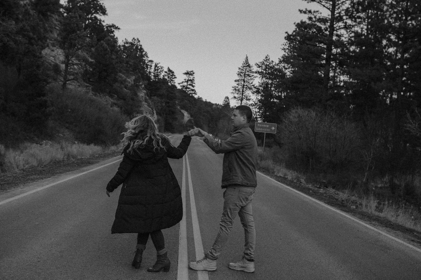 Couple dances in the road surrounded by trees on the mountaintop