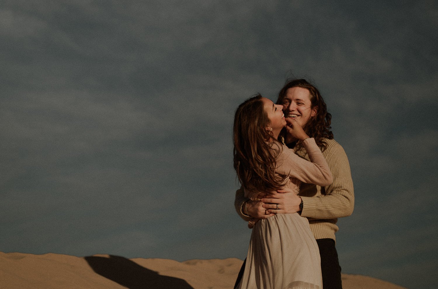 Sand dunes elopement at sunset beautiful couple laughs in the sand