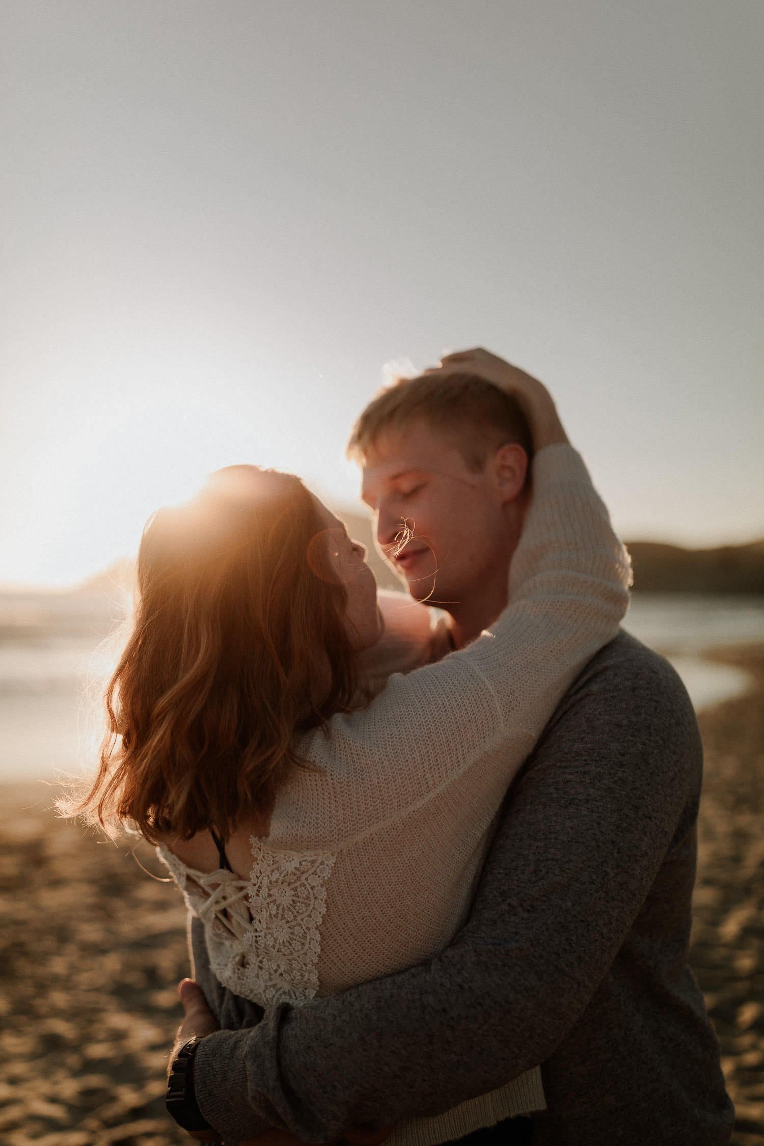 Casual bride embraces her new husband at sunset on the beach right after their elopement ceremony