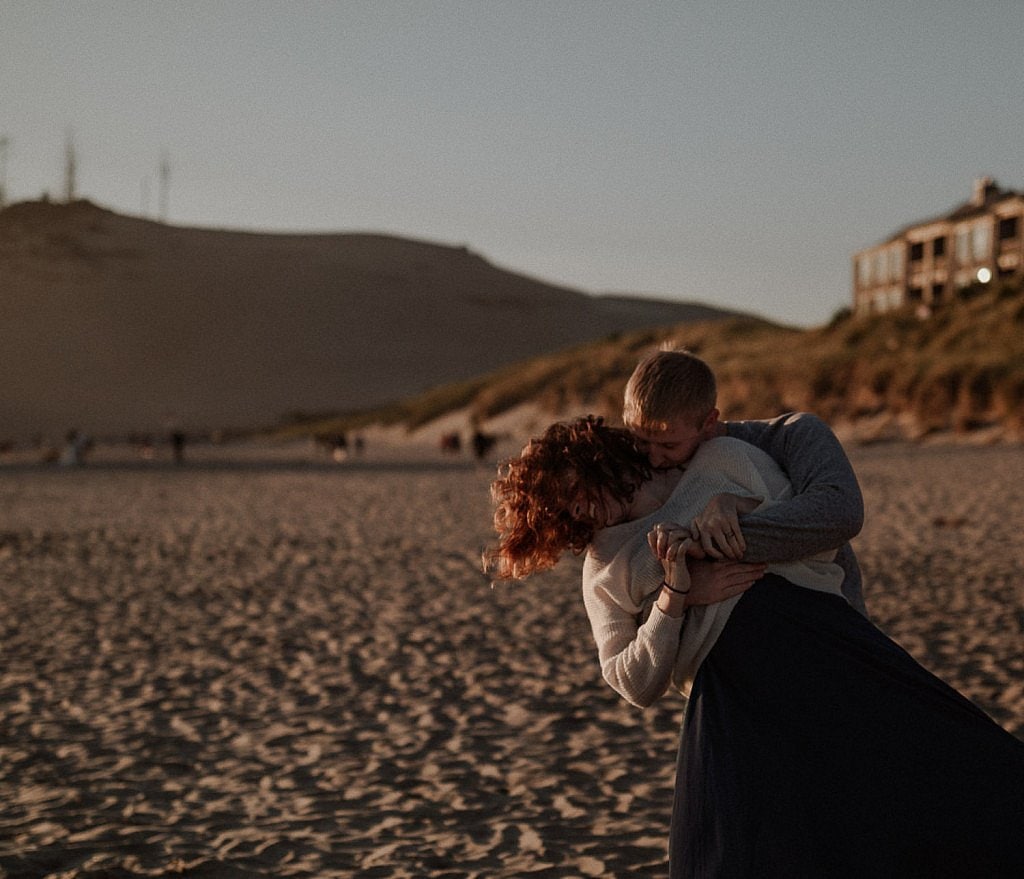 Groom tickles his bride in the glow of the sunset before their elopement ceremony on the coast of Oregon. Cape Kiwanda was the perfect spot for a romantic ceremony