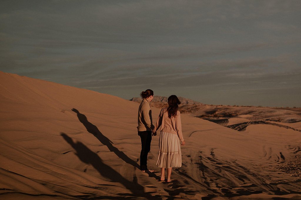 Sand dune couples adventure session with long shadows at sunset