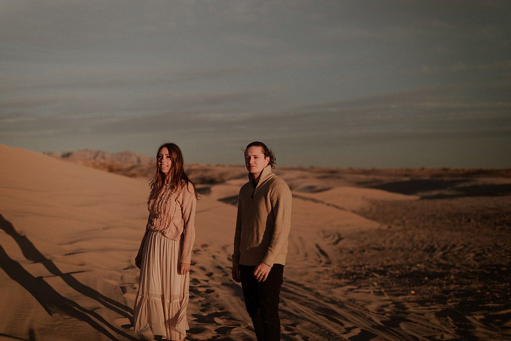 Moody couples session in the sand dunes at sunset