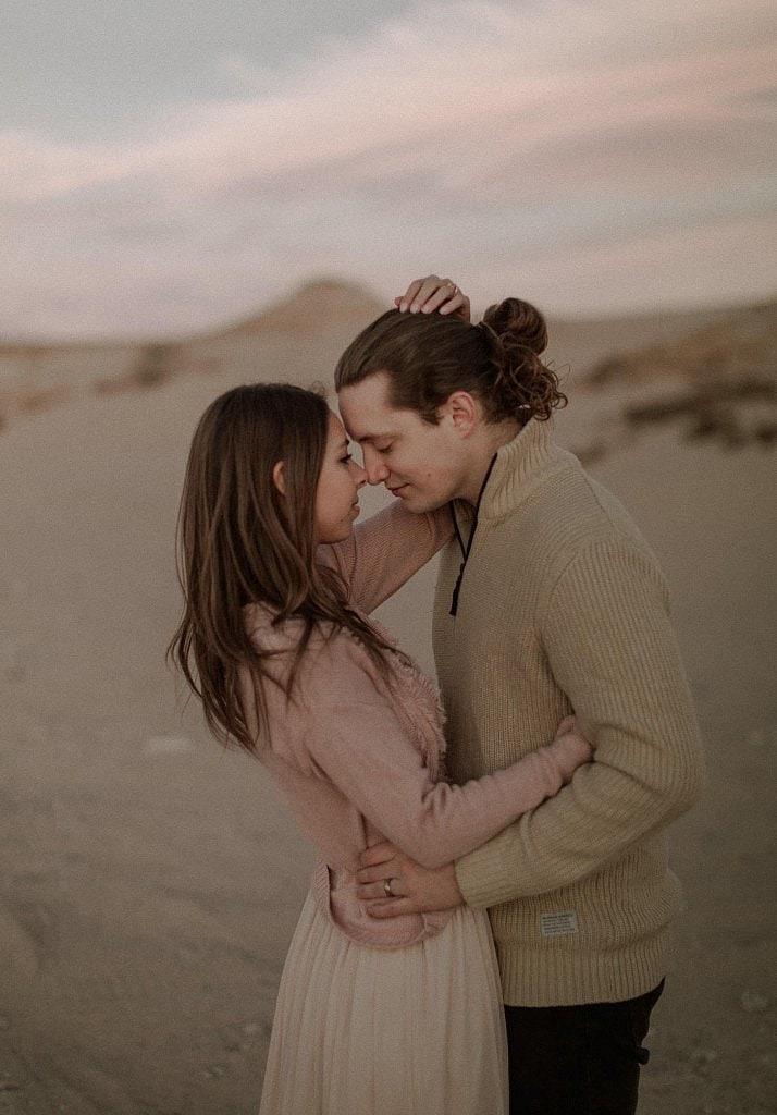 Gentle touching and hugging during romantic sand dune couples session