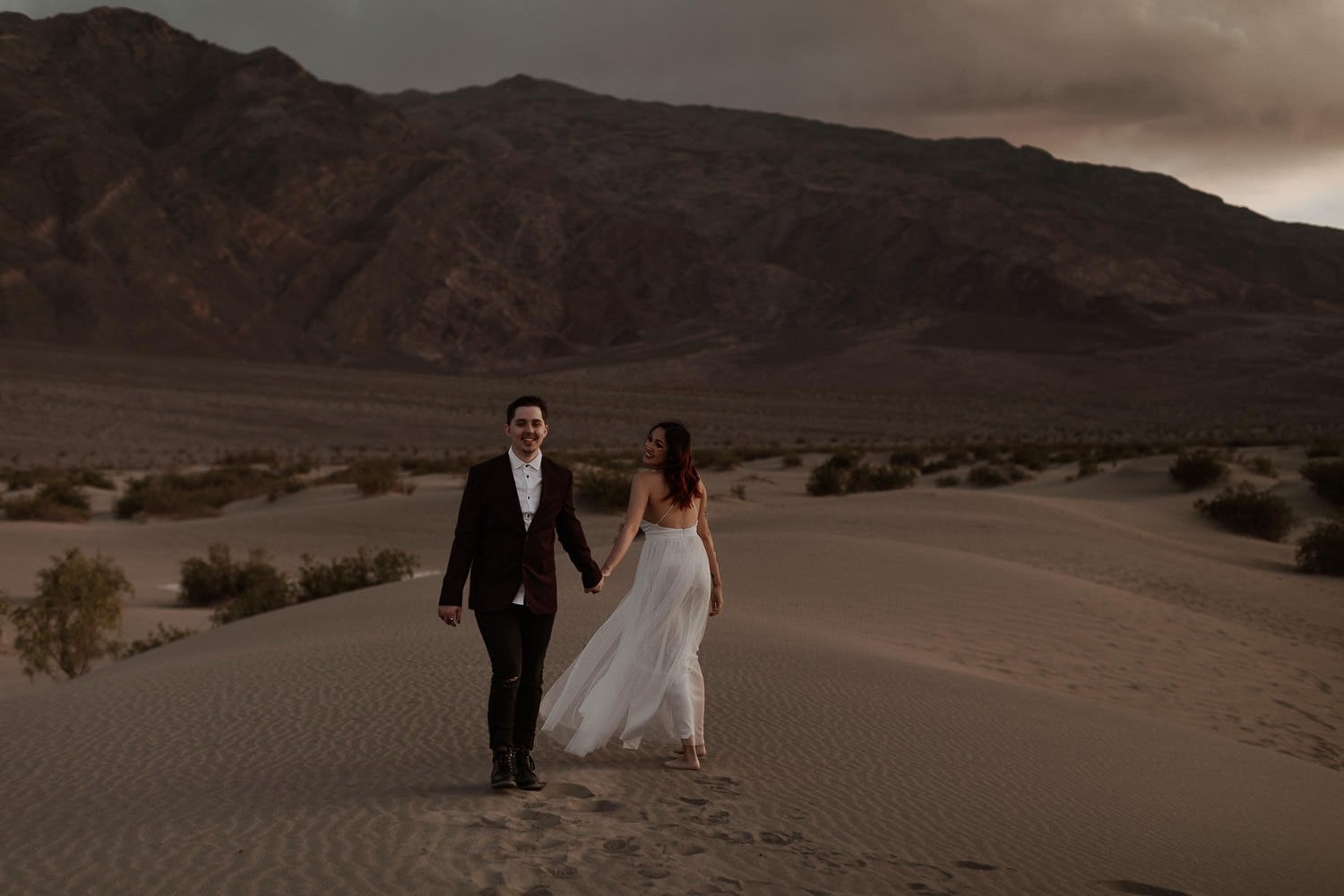 Elopement couple walk along the sand dunes, enjoying their time together after their small wedding ceremony