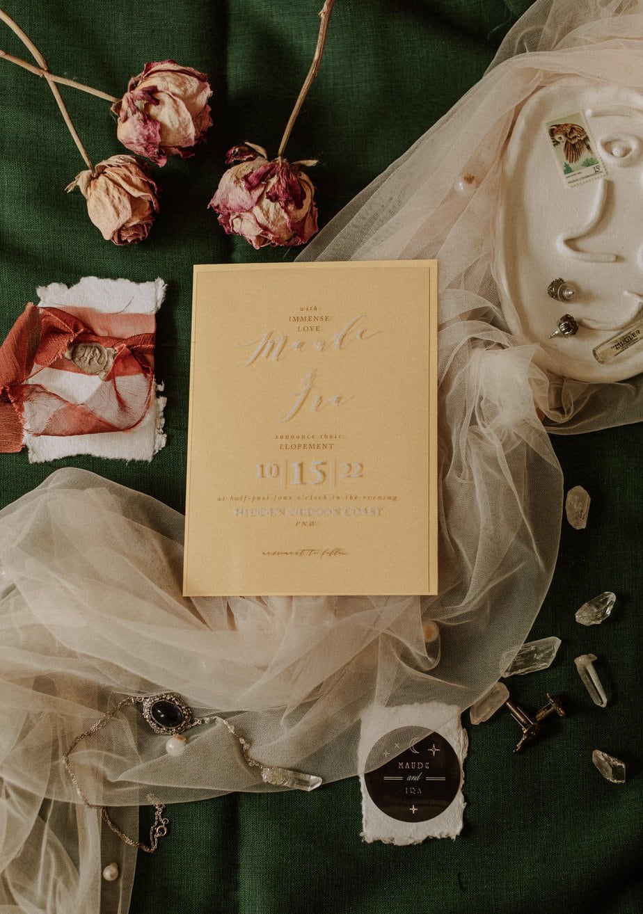 Flatlay invitation styling for an Oregon adventure elopement with dried roses and quartz jewelry