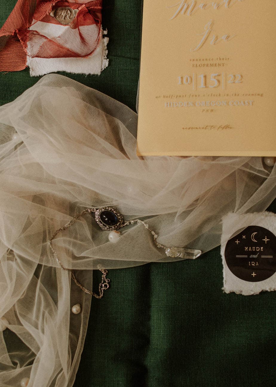 Close up of clear elopement announcement with bridal veil and handmade necklace