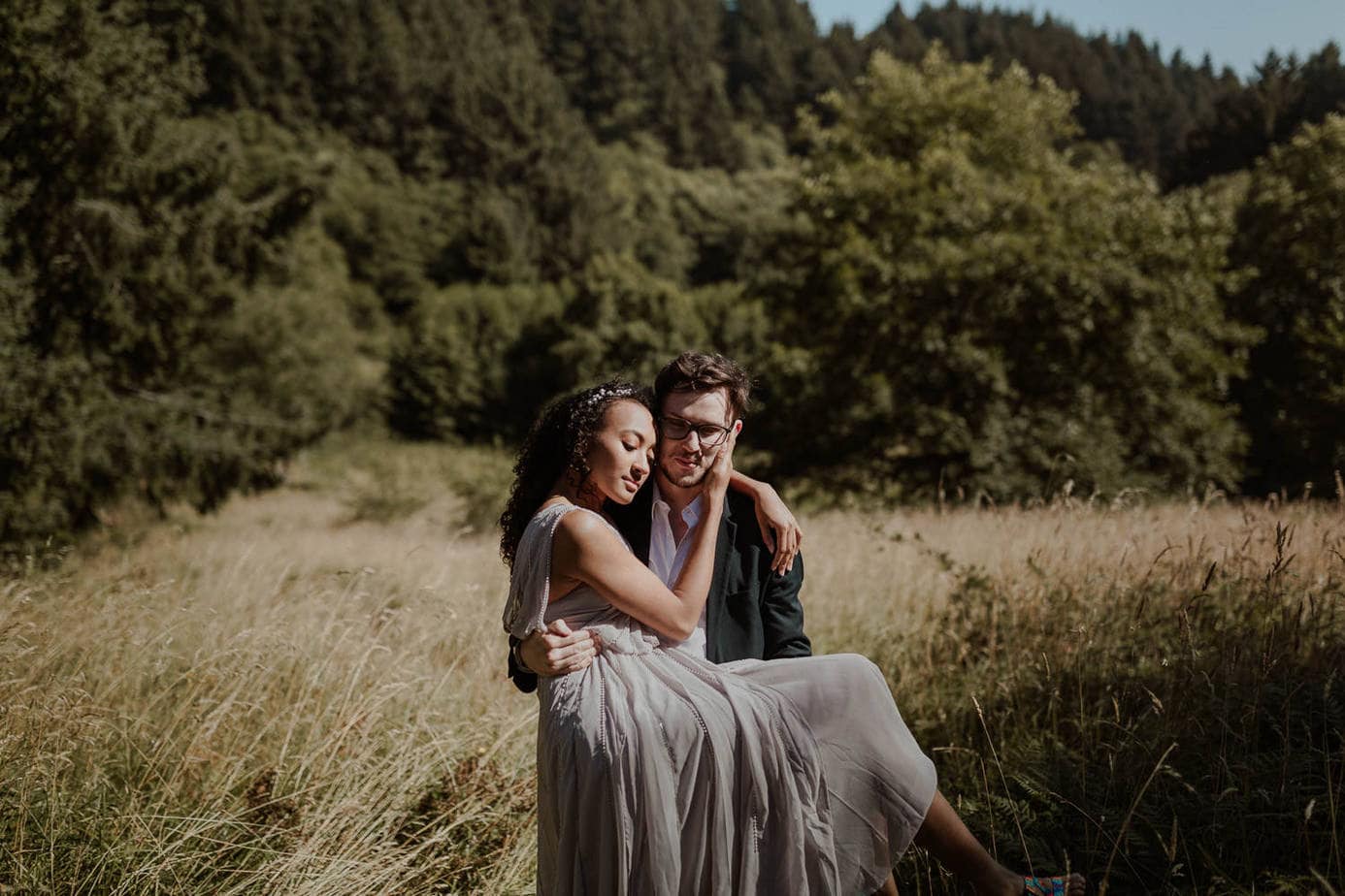 Groom carries his bride through the tall grass on the Oregon coast