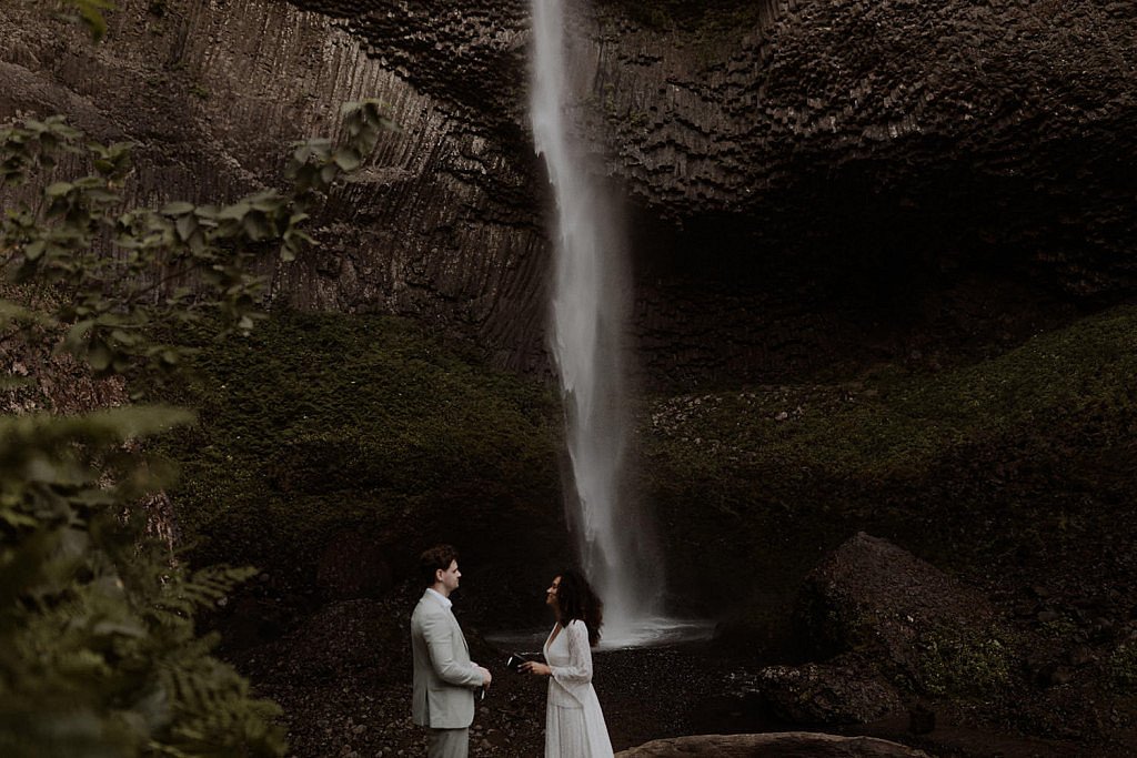 Landscape image of how big Latourell Falls is. Wedding couple say their vows to each other in the middle of the canyon