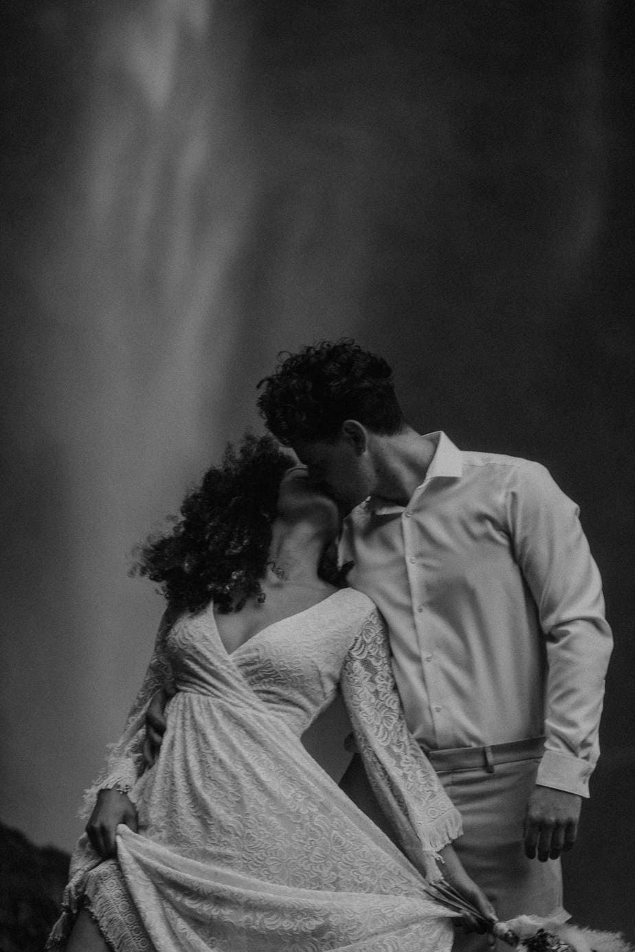 Black and white image of wedding couple kissing in front of Latourell Falls for their Oregon waterfall elopement
