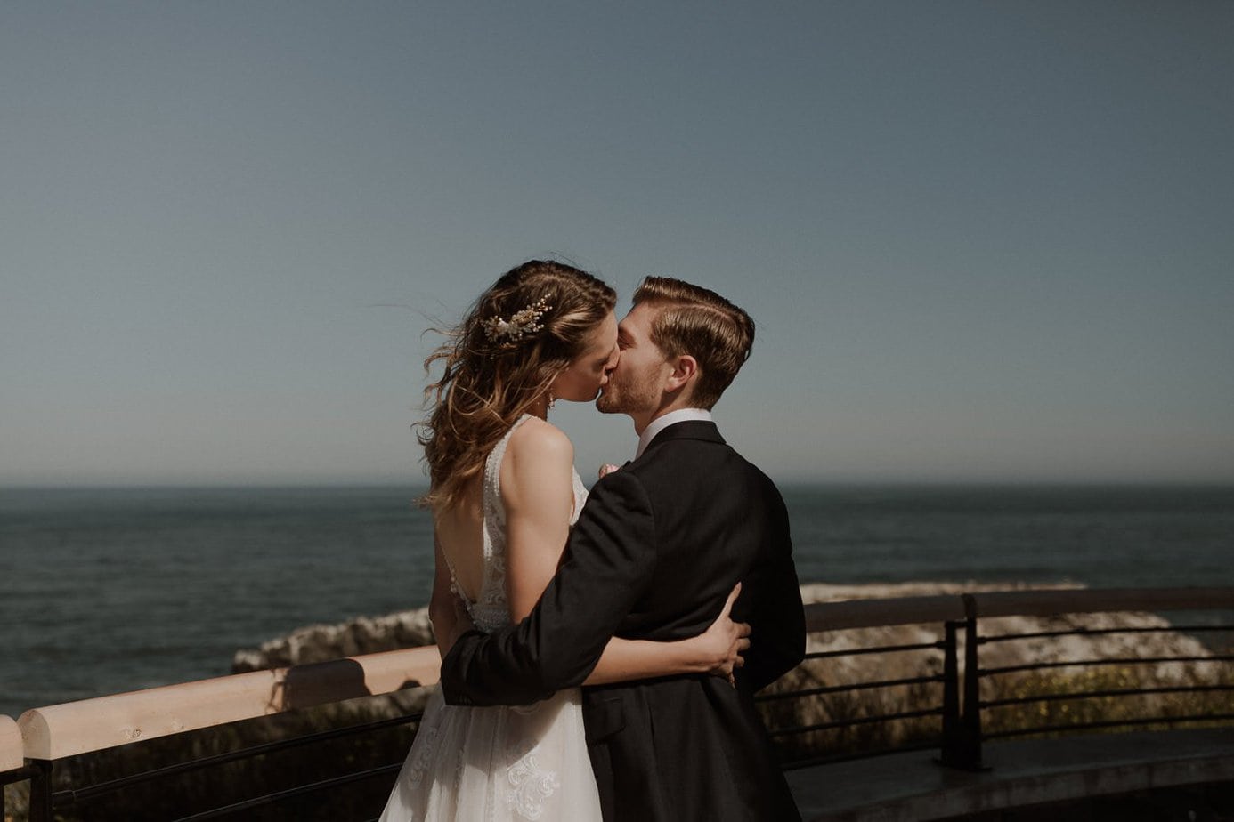 Wedding couple kiss on the pier at Yaquina Head lighthouse in Oregon