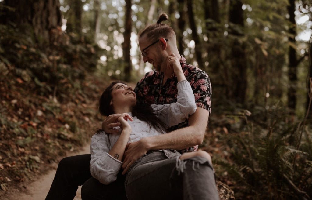 Portland engagement couple sits on log in forest park