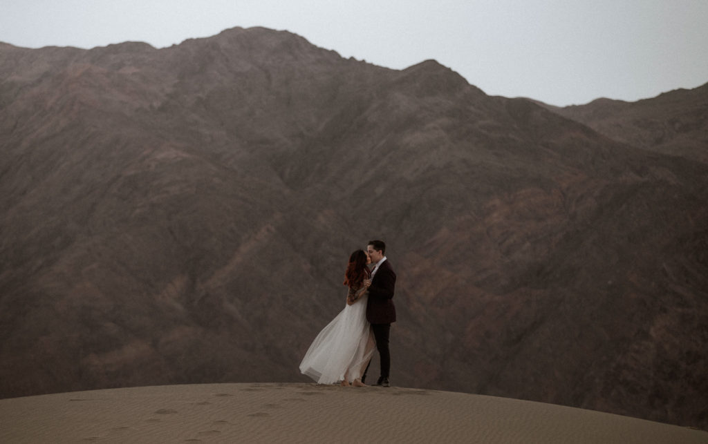 Bride and groom dance on top of the sand dunes during their intimate elopement
