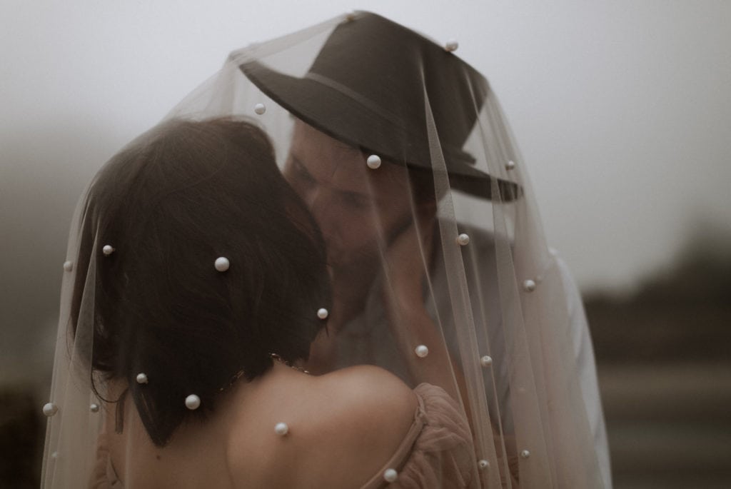 Bride and groom kiss passionately under her veil during their Oregon coast elopement