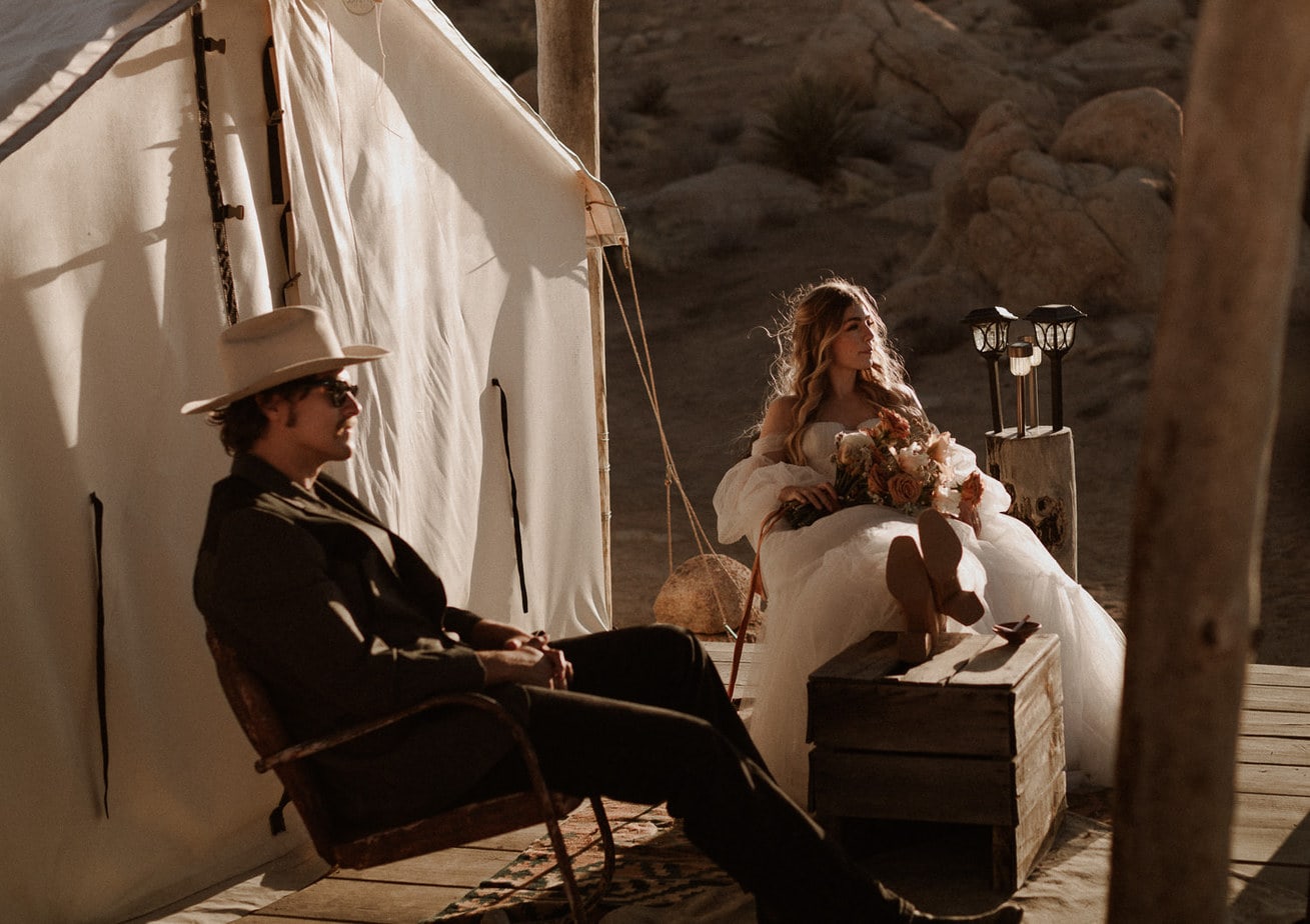 Bride and groom sit on chairs outside of yurt in the desert for their elopement