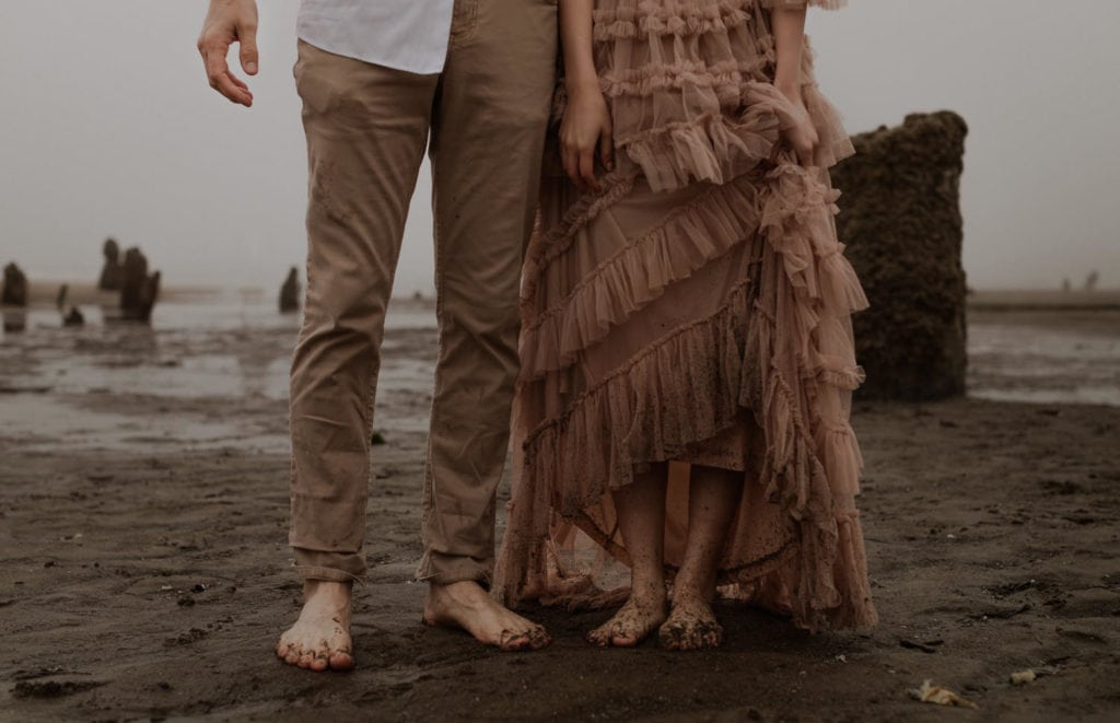 Eloping couple shows their sandy feet. Bride's tan dress is wet at the bottom