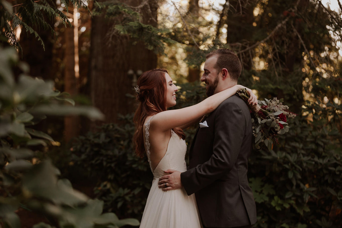 Bride and groom dance in the forest. Redwoods surround them in the background and bride smiles at groom. Knowing how much it costs to elope can help you plan our wedding day to its fullest