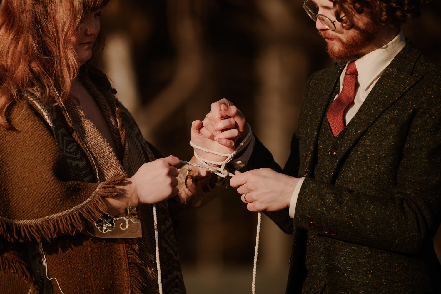 Eloping couple wrap a white cord around their hands in celtic hand fasting ceremony
