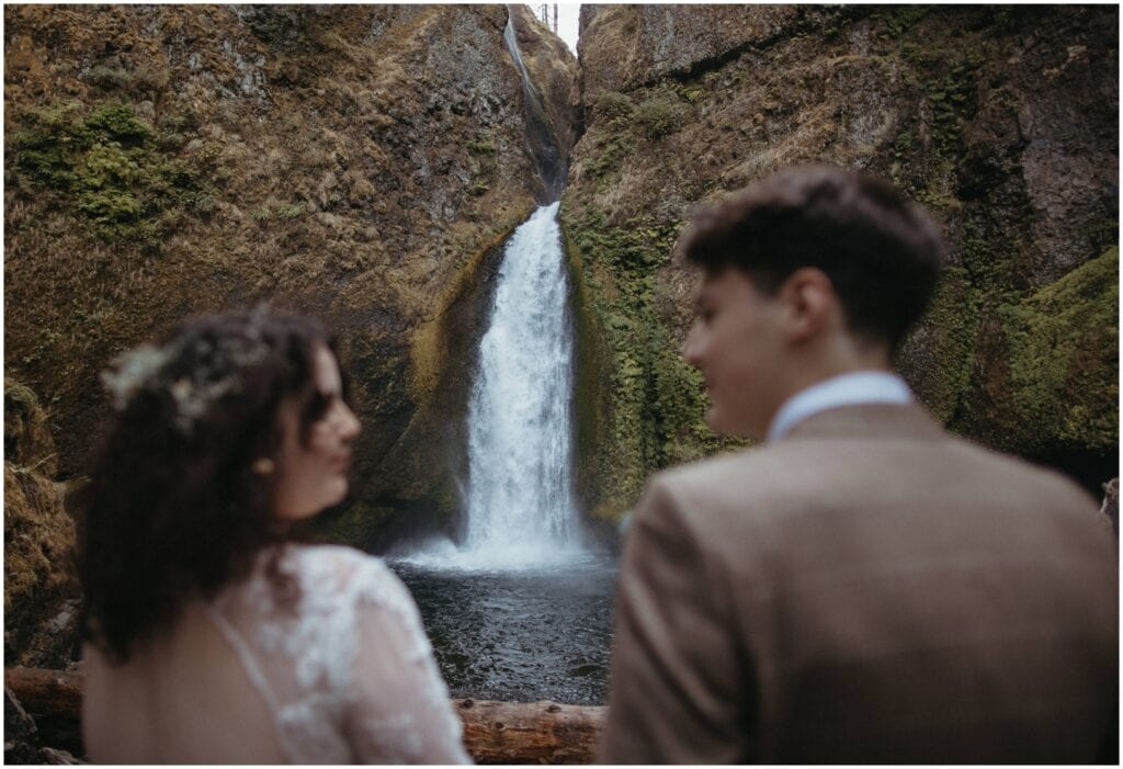 Bride and groom look into each others eyes in front of Wahclella falls