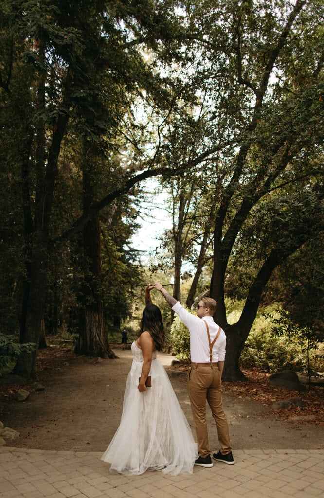 groom twirls bride on footpath in botanical garden
