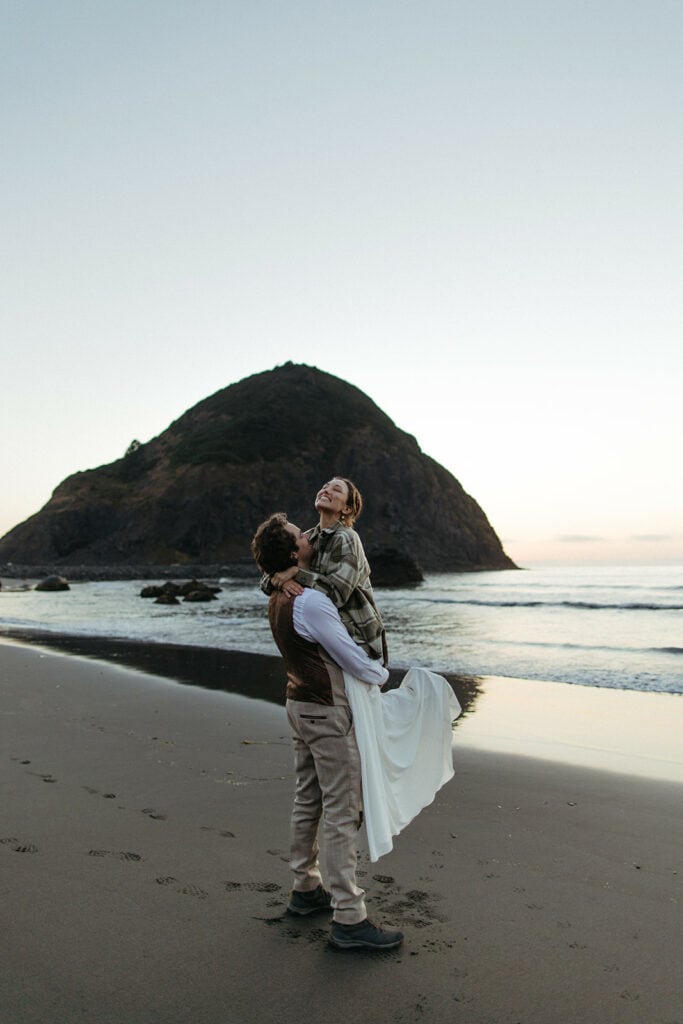 groom holding wife on the beach at Oregon Coast
