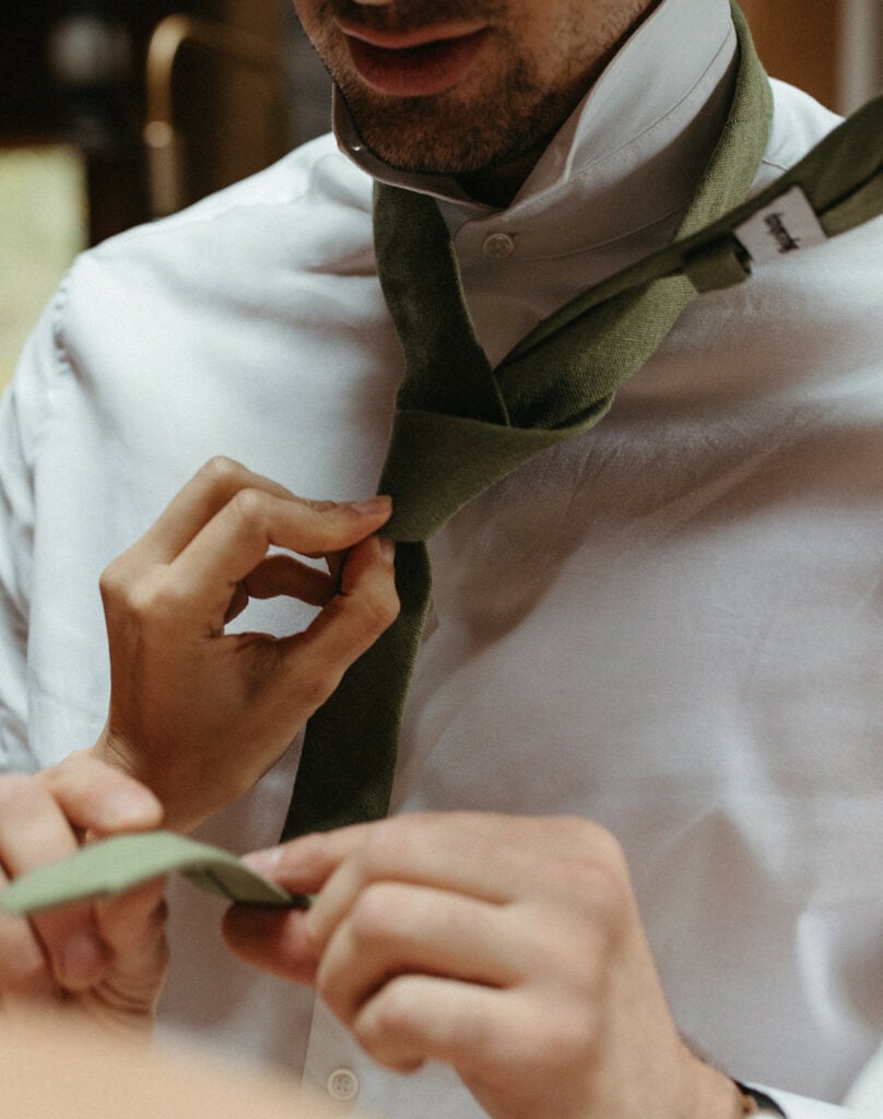 close up of bride fixing grooms tie 