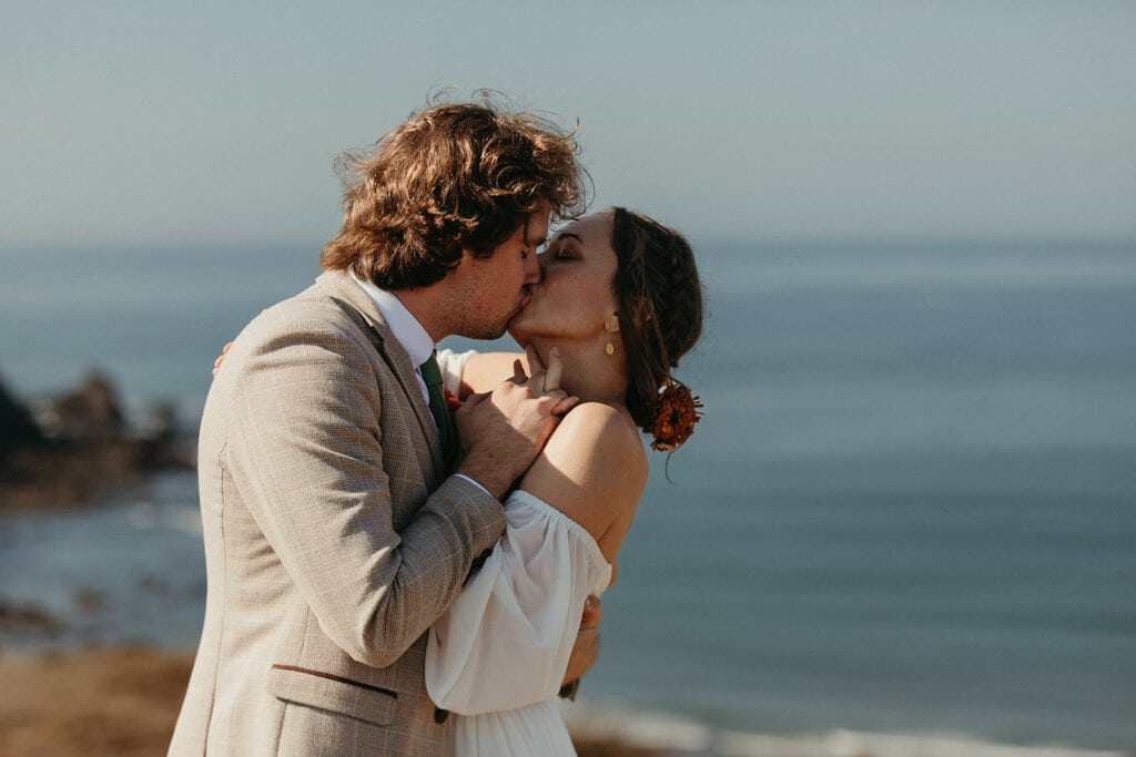 bride and groom first kiss on cliffside on the Oregon Coast