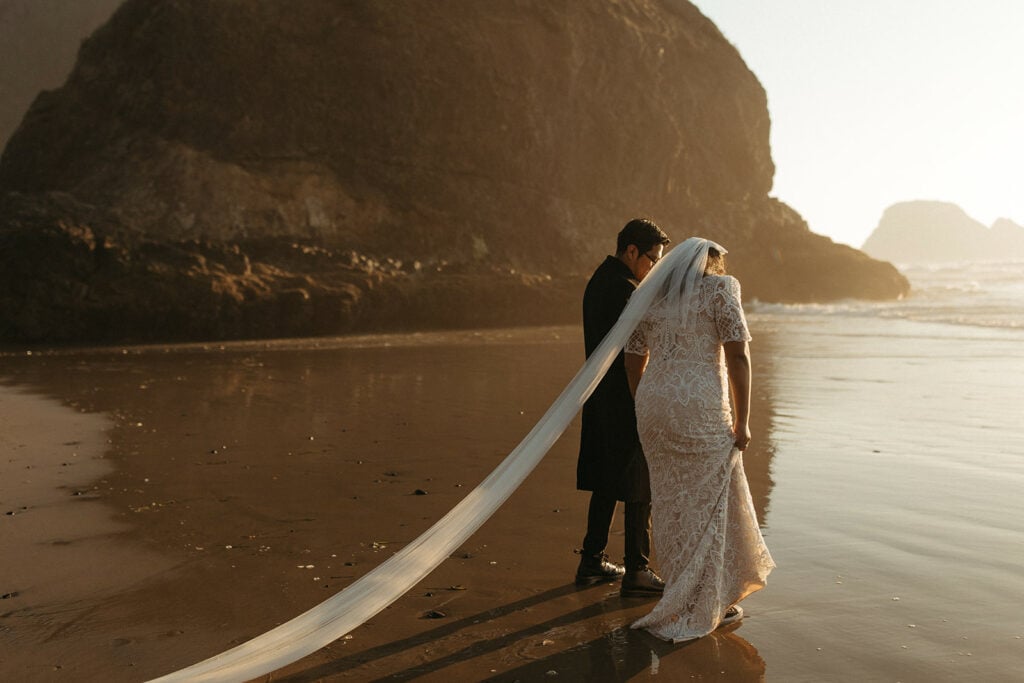 bride and groom walking along the beach during golden hour