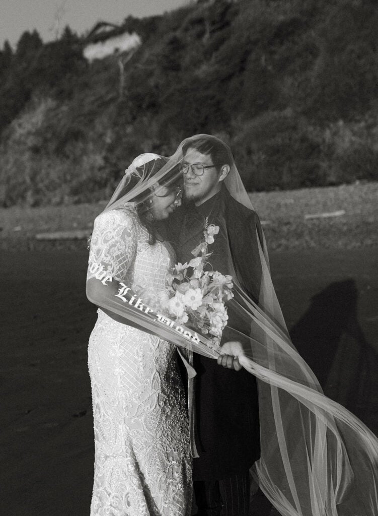 bride and groom standing on the Oregon coast will veil covering them