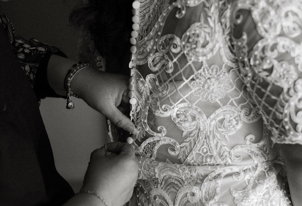 mother buttoning up brides wedding gown