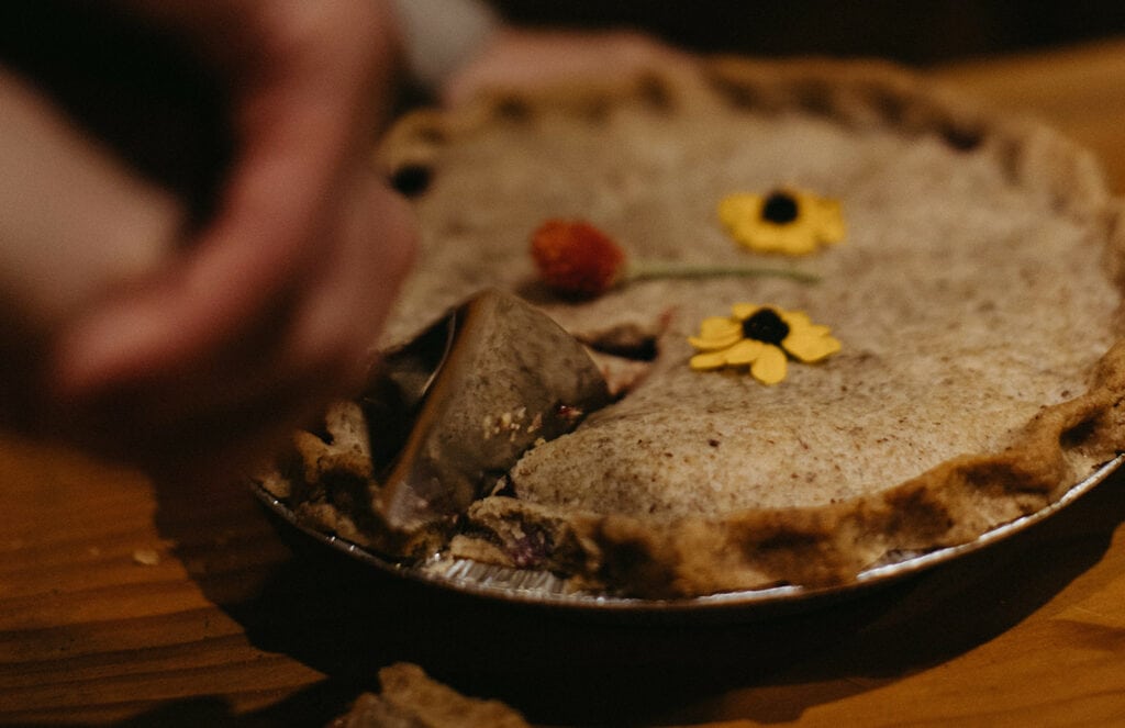 man cutting a slice of homemade pie with flowers on top