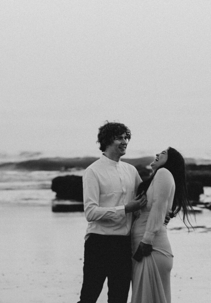 Bride and groom laugh on the beach in this candid elopement photo