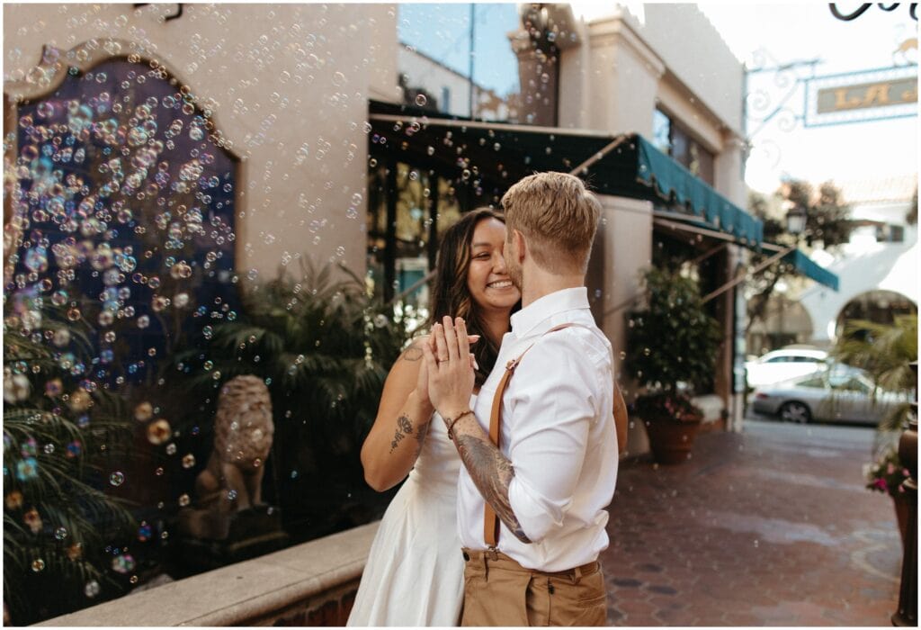 candid shot of bride and groom staring at each other with bubbles all around them 