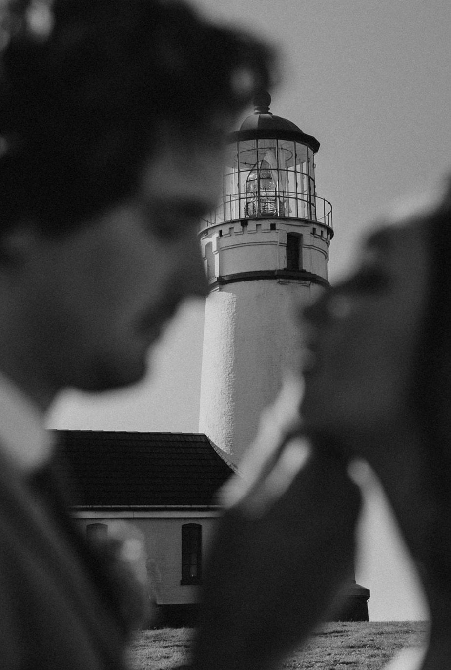 bride and groom black and white shot lighthouse in the background