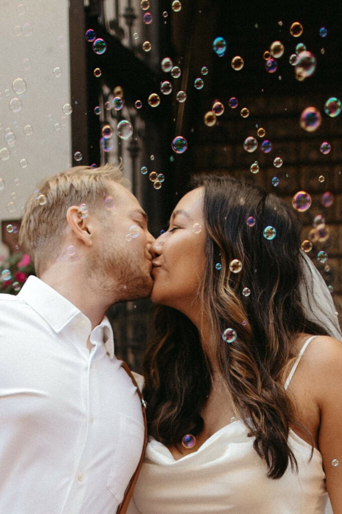 bride and groom kissing through bubbles 
