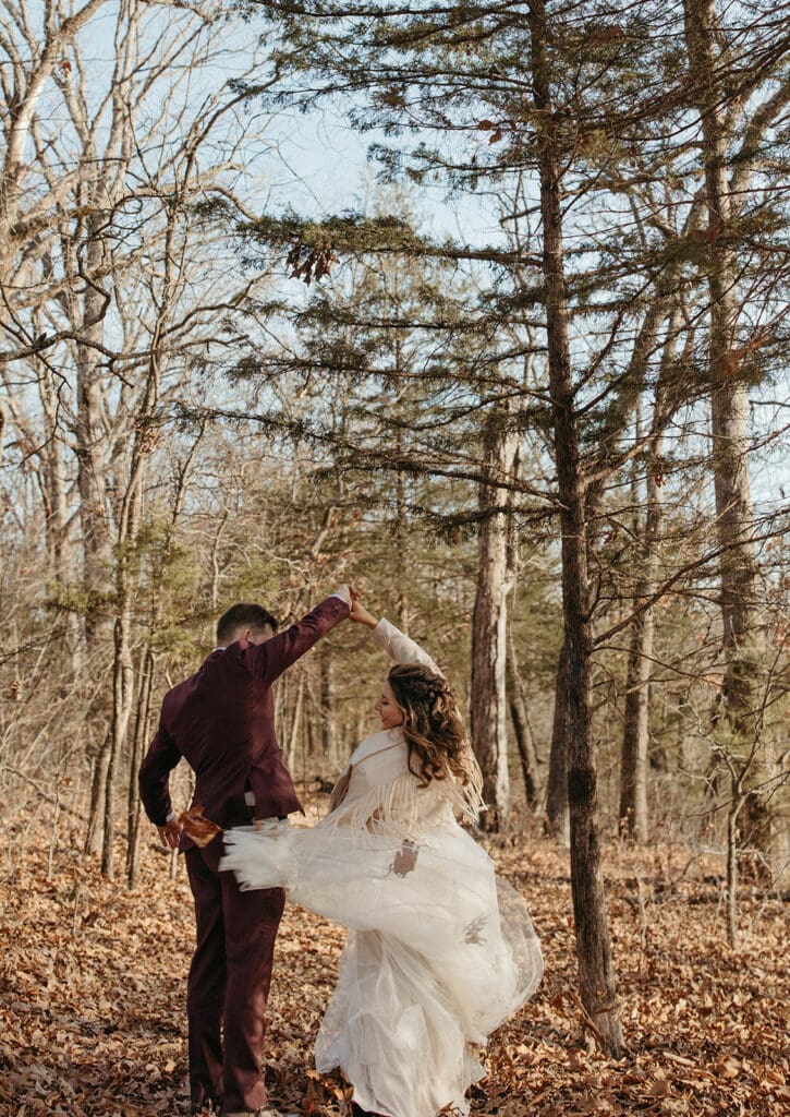 Jessi and Nate dancing in the woods in what's left of the fall foliage