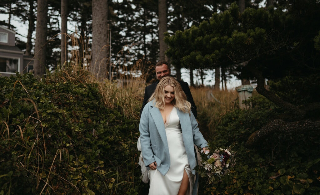 bride and groom hiking down to the beach for their couple portraits