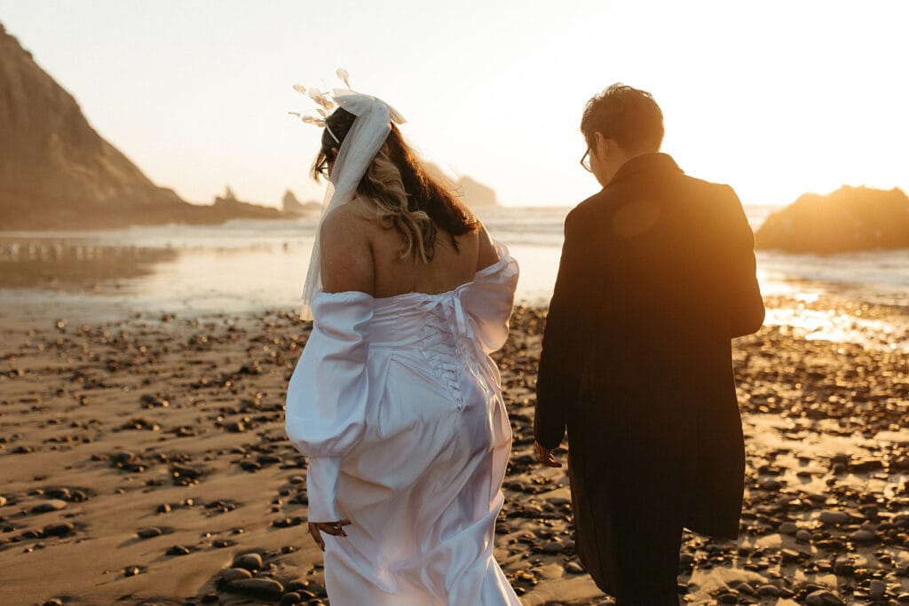 A couple walking the beach after their Cape Meares elopement ceremony.