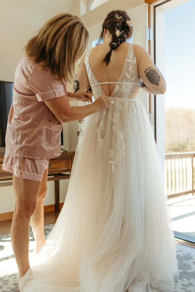Brides mother helping her with the back of her dress