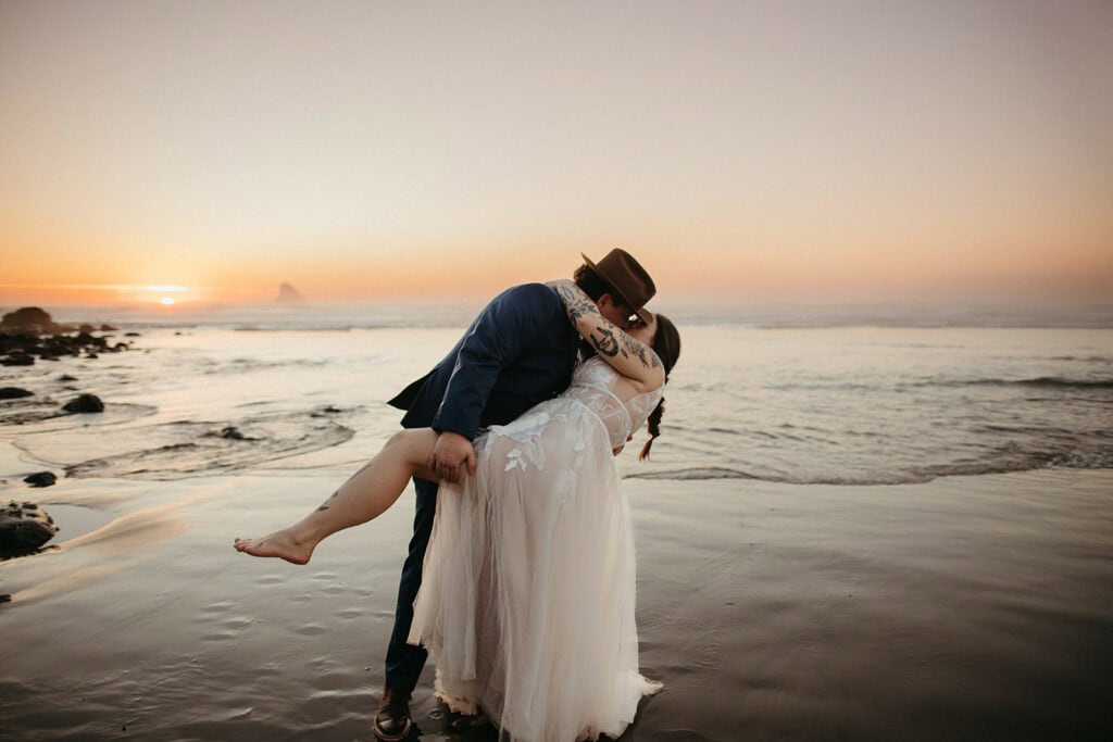 bride and groom dip and kiss at sunset on the beach