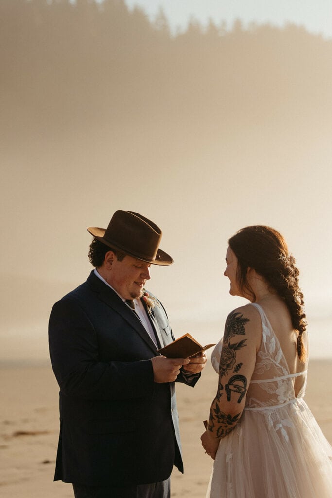 Groom reads vows during sunset beach ceremony