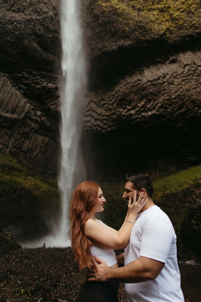 Adventurous engagement photos at the base of a PNW waterfall